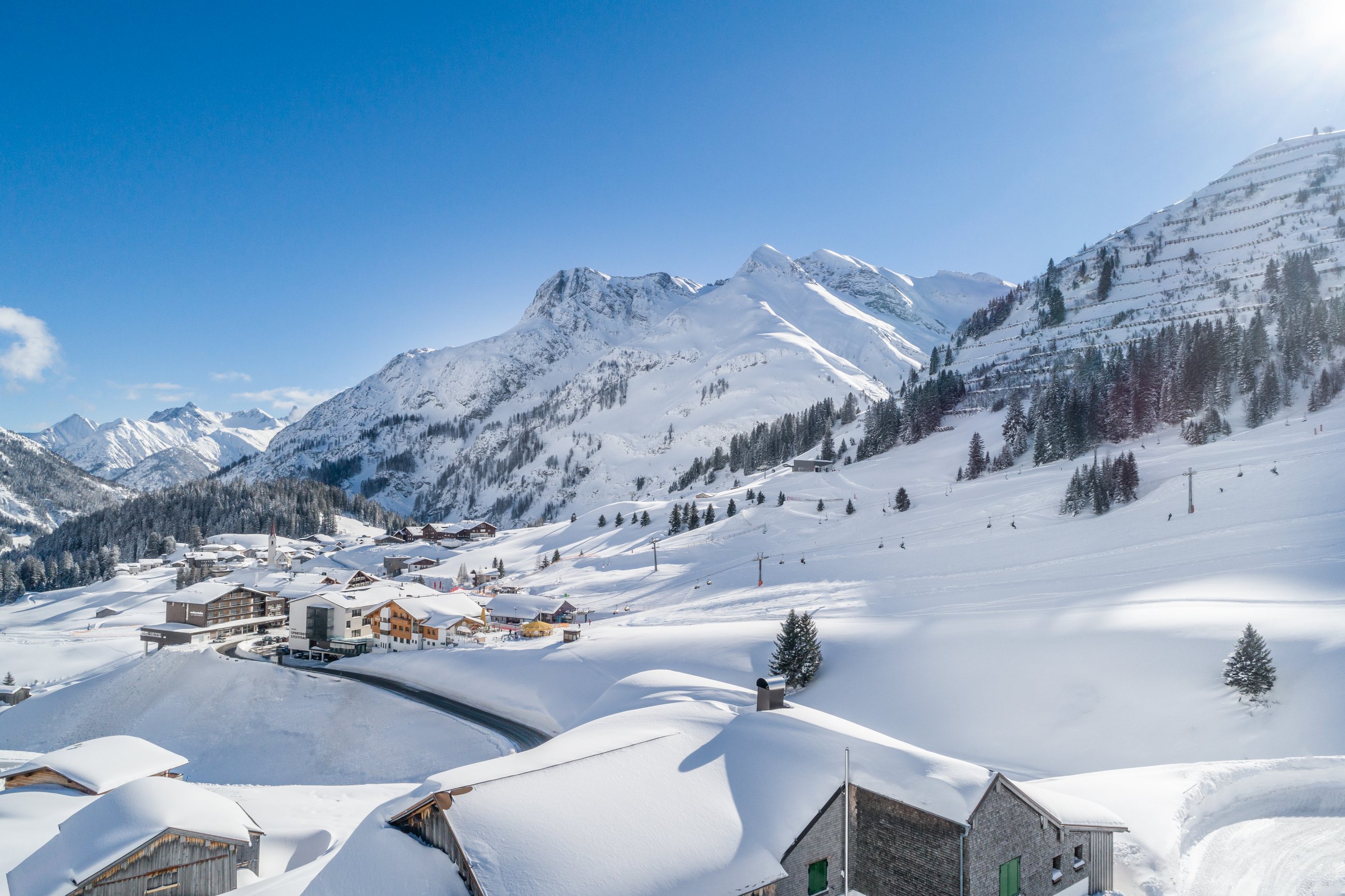 Sonniger Blick auf Warth mit Bergpanorama und Skipiste